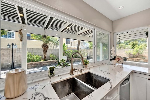 kitchen featuring plenty of natural light, a sink, light stone countertops, dishwasher, and recessed lighting