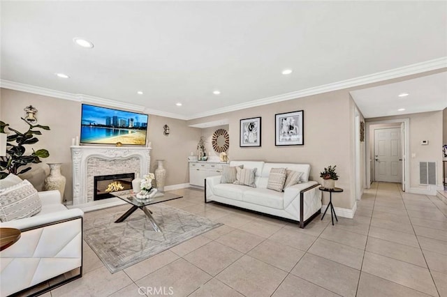living area featuring recessed lighting, light tile patterned floors, baseboards, ornamental molding, and a glass covered fireplace