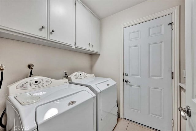 laundry area featuring separate washer and dryer, cabinet space, and light tile patterned flooring