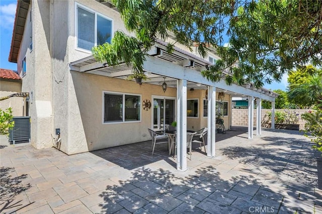 rear view of property with a pergola, stucco siding, fence, a patio area, and central AC unit