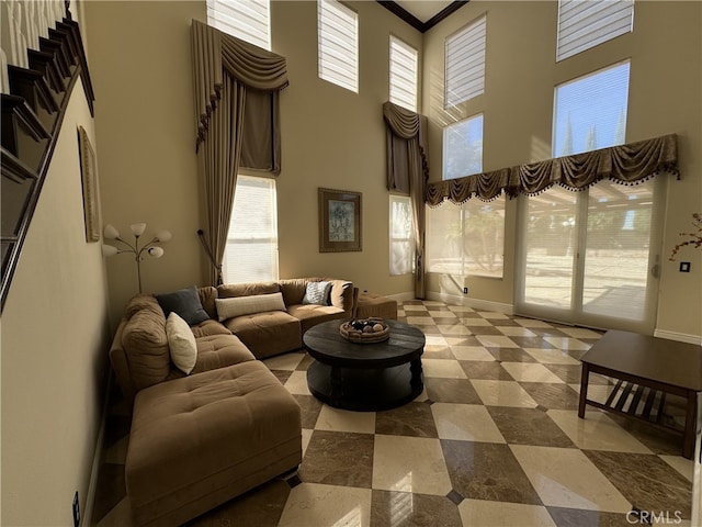 living area with baseboards, a towering ceiling, and plenty of natural light
