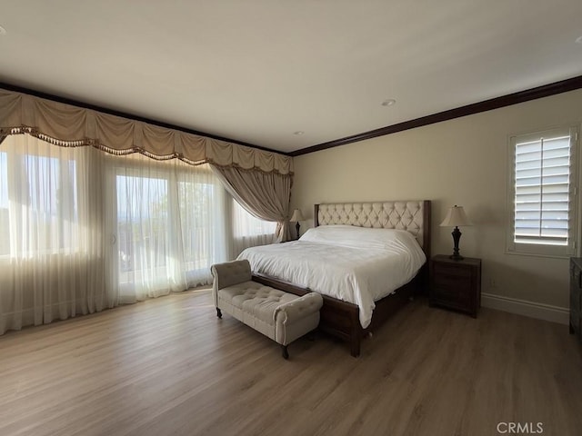 bedroom featuring baseboards, wood finished floors, and crown molding