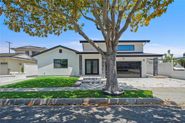 traditional-style house with fence, stucco siding, an attached garage, driveway, and french doors