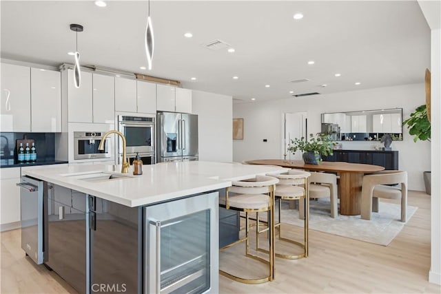 kitchen featuring white cabinets, modern cabinets, stainless steel appliances, and wine cooler