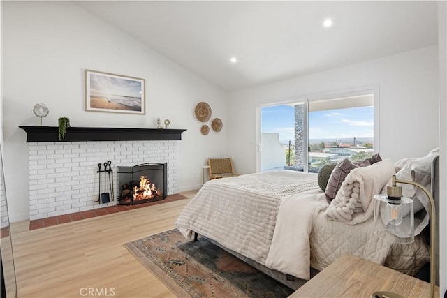 bedroom with a fireplace, vaulted ceiling, wood finished floors, and recessed lighting
