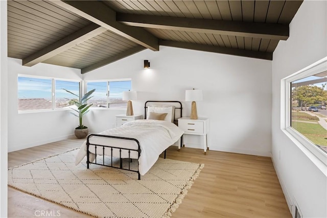 bedroom with light wood-style flooring, baseboards, and lofted ceiling with beams