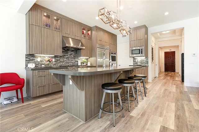 20512 W Esmeralda Ln, Porter Ranch, CA 91311 - kitchen with range hood, appliances with stainless steel finishes, modern cabinets, dark countertops, and a breakfast bar area