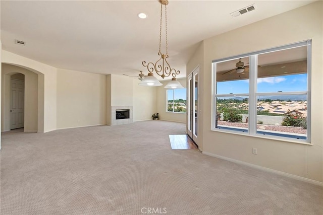 5536 Breckenridge Ave, Banning, CA 92220 - unfurnished living room featuring light colored carpet, arched walkways, a tiled fireplace, and baseboards