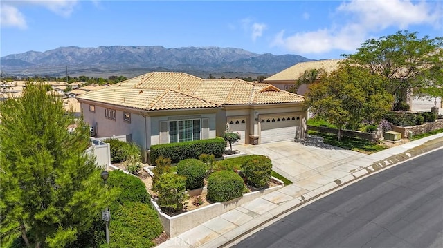 5536 Breckenridge Ave, Banning, CA 92220 - mediterranean / spanish-style home with a garage, a mountain view, concrete driveway, a tile roof, and stucco siding