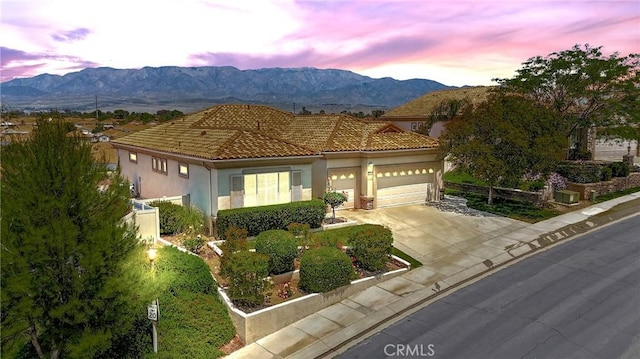 5536 Breckenridge Ave, Banning, CA 92220 - mediterranean / spanish-style home with an attached garage, concrete driveway, a mountain view, and stucco siding