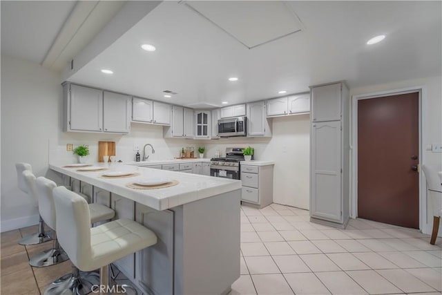 kitchen with a breakfast bar area, a peninsula, stainless steel appliances, and recessed lighting