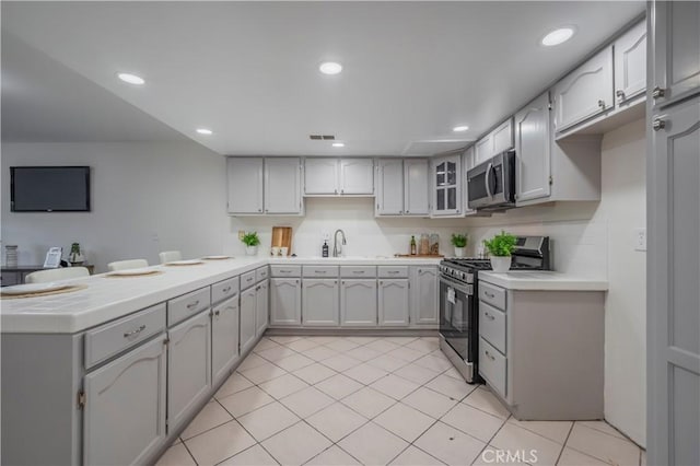 kitchen with a peninsula, a sink, visible vents, appliances with stainless steel finishes, and light tile patterned floors