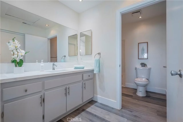 bathroom featuring wood finished floors, visible vents, toilet, vanity, and baseboards