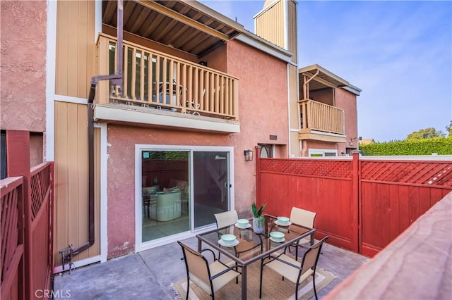 view of patio / terrace featuring fence, a balcony, and outdoor dining space