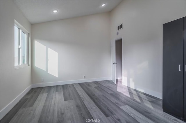 unfurnished room featuring recessed lighting, wood finished floors, visible vents, and baseboards