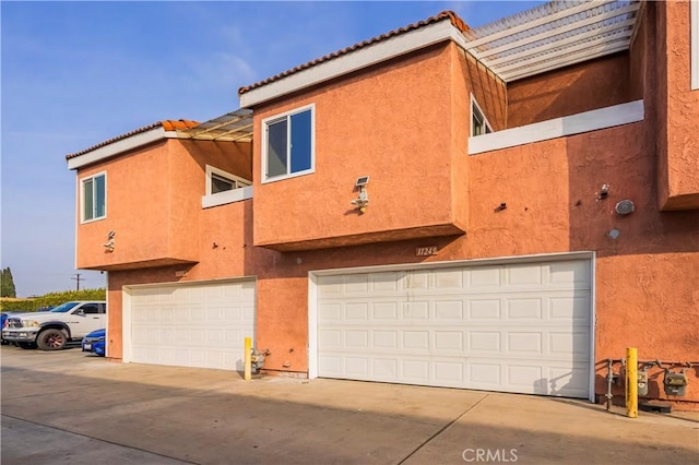 view of home's exterior featuring a garage, a tile roof, and stucco siding