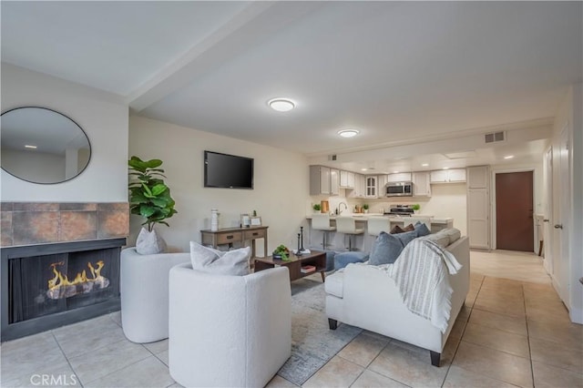 living area with a tile fireplace, visible vents, and light tile patterned floors