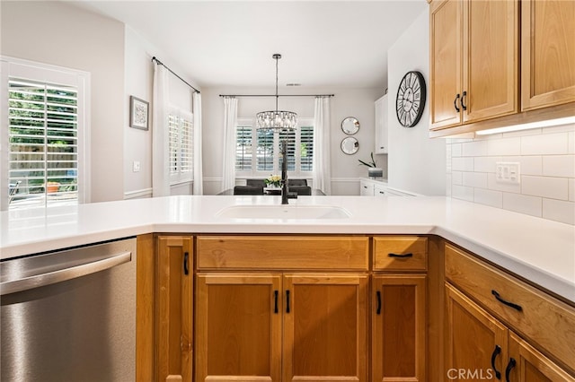 kitchen featuring tasteful backsplash, dishwasher, a wealth of natural light, light countertops, and a notable chandelier
