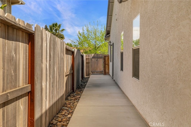 view of side of property with fence, a gate, and stucco siding