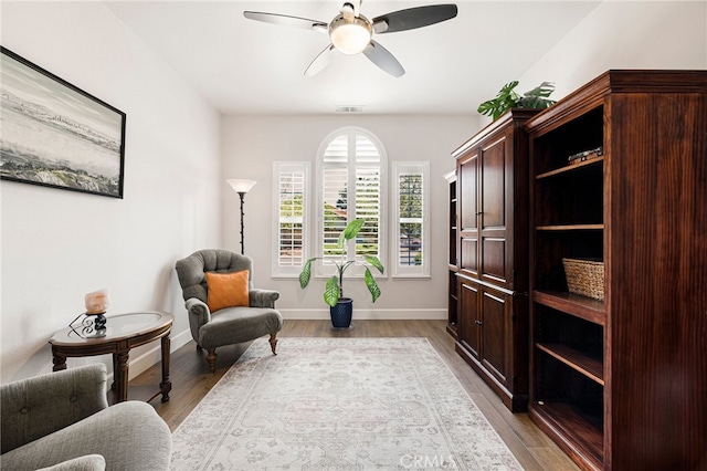 sitting room with light wood-style flooring, visible vents, baseboards, and ceiling fan