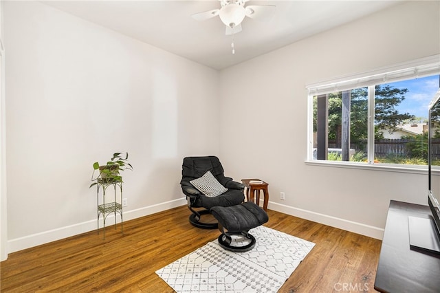 living area featuring wood finished floors, baseboards, and ceiling fan