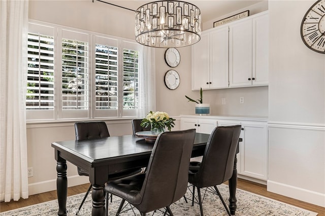dining area with baseboards, a notable chandelier, and light wood finished floors