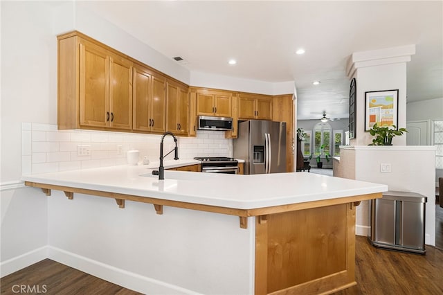 kitchen featuring a peninsula, light countertops, dark wood-type flooring, and stainless steel appliances