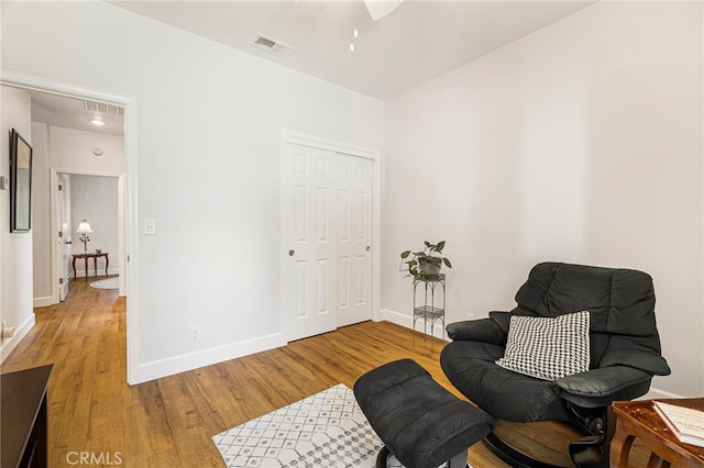 living area featuring baseboards, wood finished floors, and visible vents
