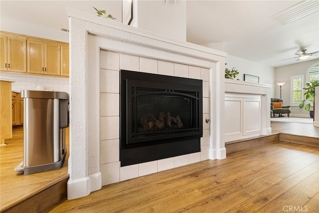 room details featuring a fireplace, backsplash, wood finished floors, and ceiling fan