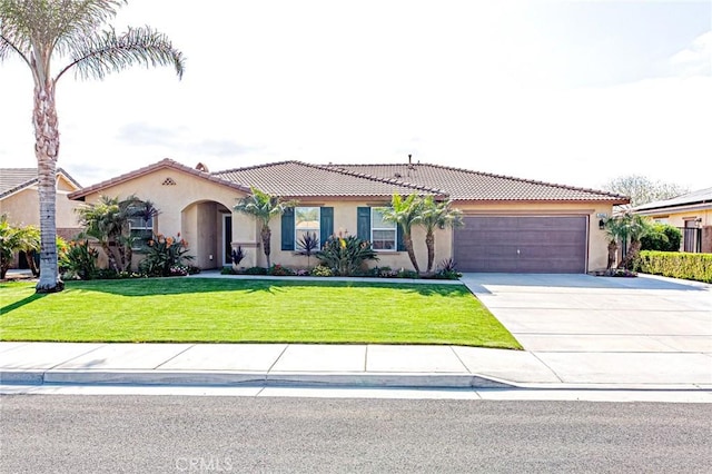 mediterranean / spanish home featuring a garage, stucco siding, driveway, and a tiled roof