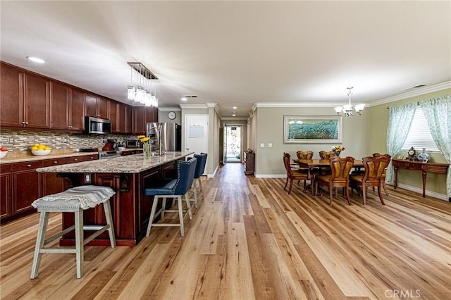 kitchen featuring appliances with stainless steel finishes, light wood-style flooring, ornamental molding, and baseboards