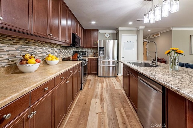 kitchen featuring ornamental molding, light wood-style floors, appliances with stainless steel finishes, and a sink