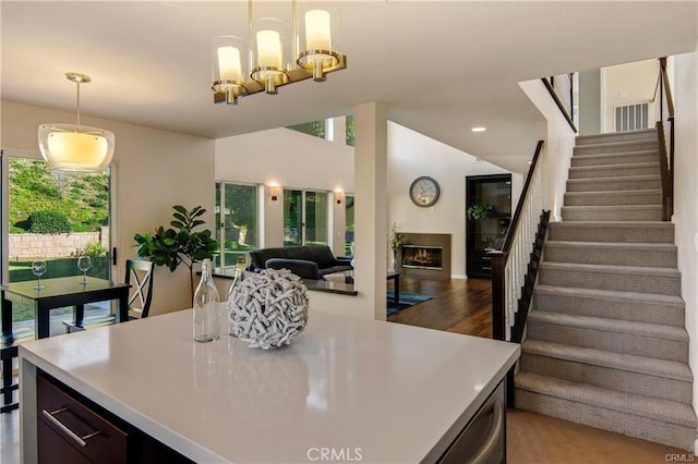 kitchen featuring open floor plan, a lit fireplace, pendant lighting, and light countertops