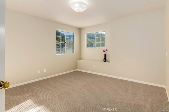 carpeted empty room featuring baseboards