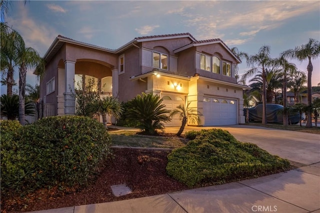mediterranean / spanish home with concrete driveway, an attached garage, and stucco siding
