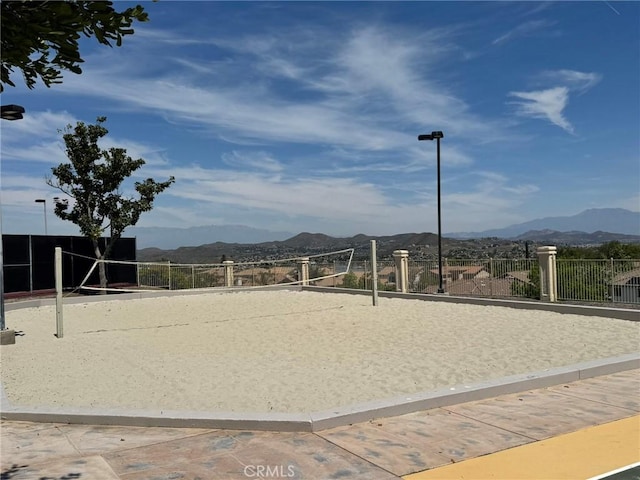 surrounding community featuring volleyball court, a mountain view, and fence