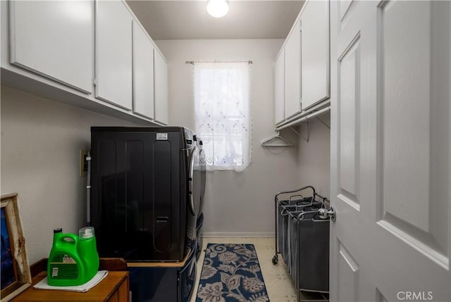 clothes washing area with baseboards, cabinet space, and washer and clothes dryer