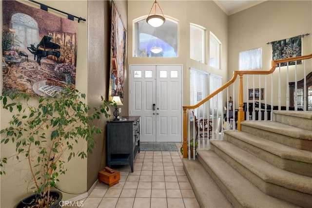 entryway featuring a high ceiling, stairs, and light tile patterned floors