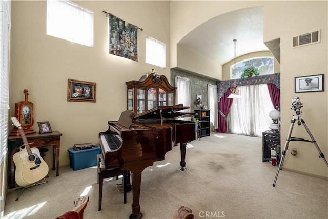 living area with arched walkways, carpet, visible vents, and high vaulted ceiling