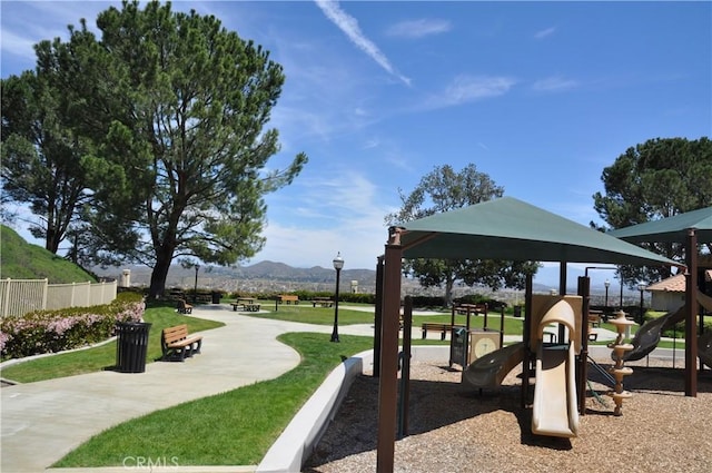 communal playground with a lawn, fence, and a mountain view
