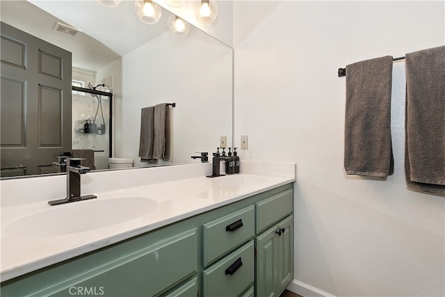 bathroom featuring double vanity, visible vents, toilet, a sink, and a stall shower