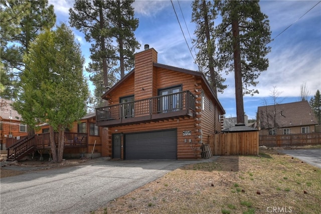 view of front of property with a chimney, fence, a garage, log exterior, and aphalt driveway