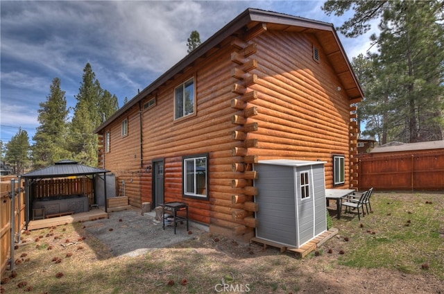 back of property with a gazebo, log exterior, a patio area, and fence