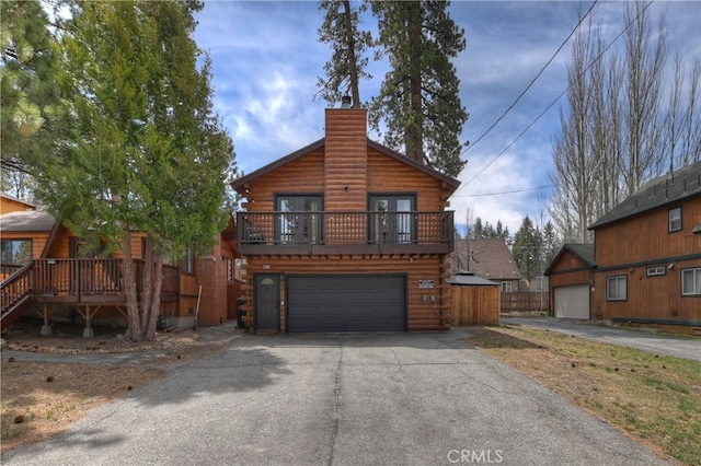 log home featuring a chimney, an attached garage, aphalt driveway, and log siding