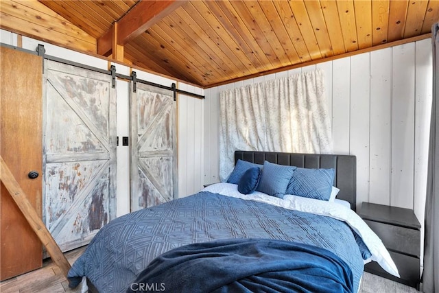 bedroom featuring a barn door, wooden walls, vaulted ceiling, wood finished floors, and wood ceiling