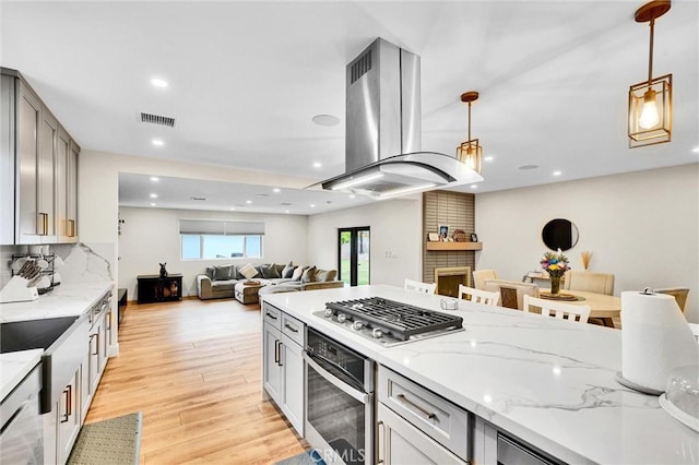 12643 Gladstone Ave, Sylmar, CA 91342 - kitchen with light wood finished floors, island exhaust hood, visible vents, light stone counters, and appliances with stainless steel finishes