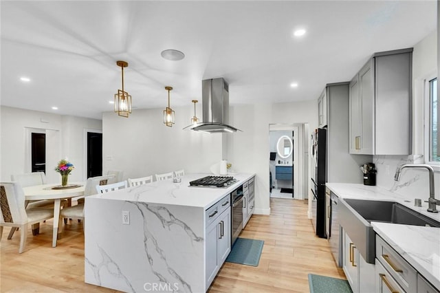 12643 Gladstone Ave, Sylmar, CA 91342 - kitchen with light stone counters, a sink, island exhaust hood, gray cabinets, and appliances with stainless steel finishes