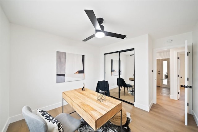 office area with baseboards, a ceiling fan, and light wood finished floors