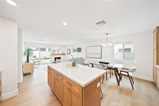 kitchen with baseboards, a kitchen island, light wood-type flooring, and visible vents