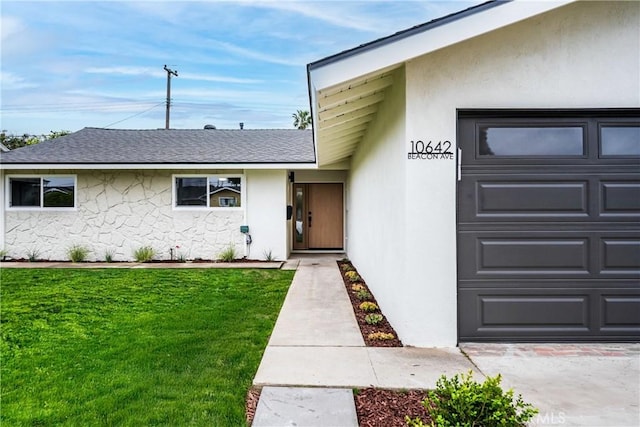 view of exterior entry with a lawn, a garage, roof with shingles, and stucco siding